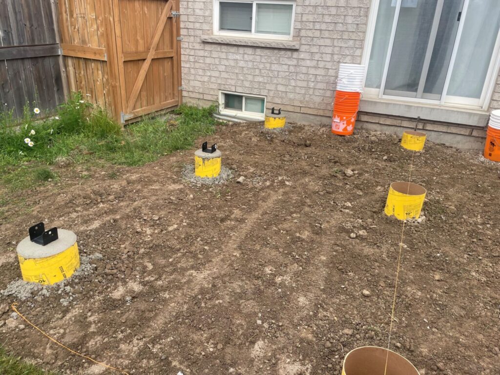 Shed footings being installed with concrete in a backyard in Essa, Ontario by Post Holes Plus.