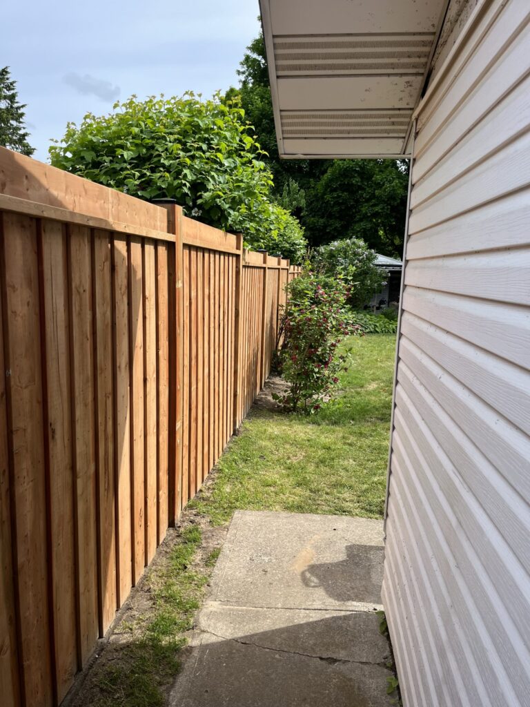 Crew constructing a wooden fence with concrete-set posts in a Barrie, Ontario backyard.