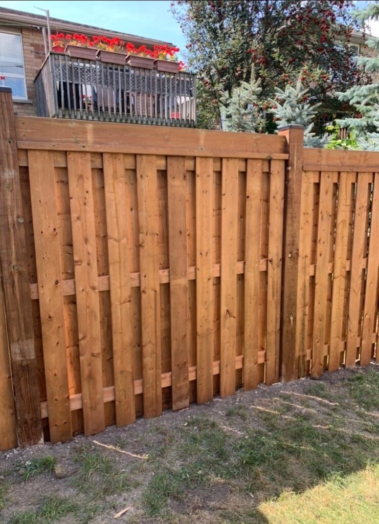 Wood fence under construction in Georgina, Ontario by Post Holes Plus, with posts and panels being installed.