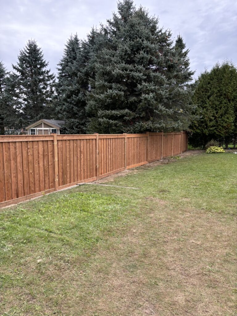 Fence under construction in Springwater by Post Holes Plus with concrete footings and wooden panels.