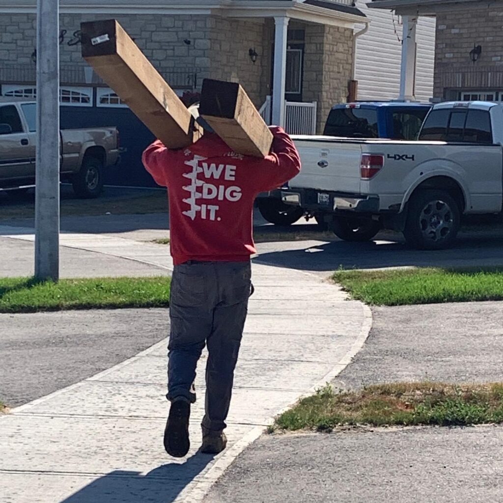 Wooden fence post being installed in New Tecumseth by Post Holes Plus with concrete footing support.